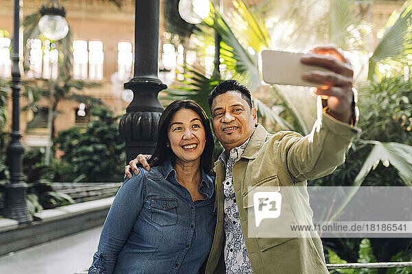 Smiling mature couple taking selfie through mobile phone