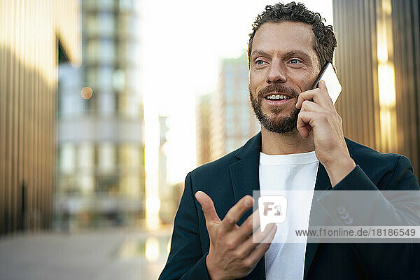 Smiling businessman gesturing and talking on mobile phone