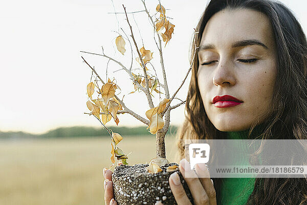 Smiling woman with eyes closed holding plant