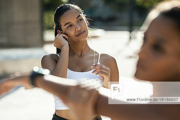 Teenage girl with friend exercising on sunny day