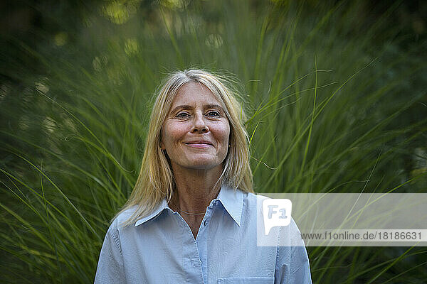Smiling mature woman standing in front of plant