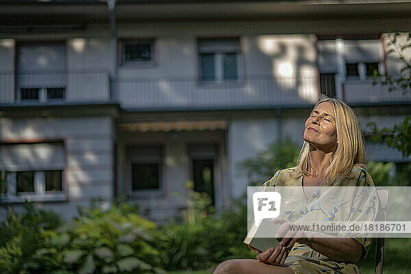 Mature woman with book relaxing in garden