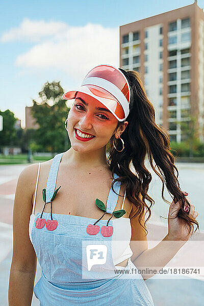 Smiling young woman wearing sun visor at sports court