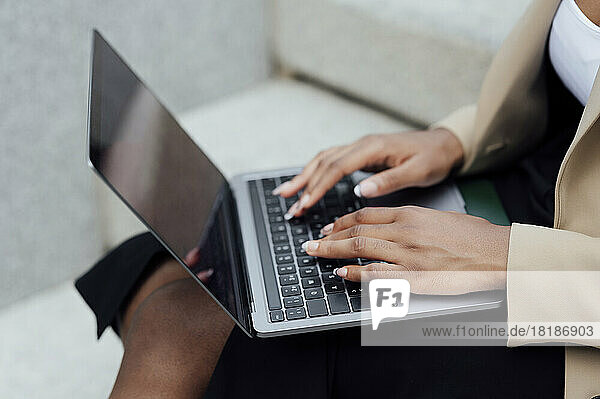 Businesswoman working on laptop sitting on bench