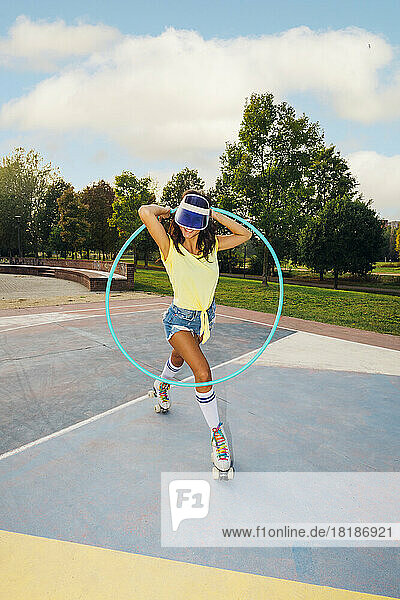 Woman with hoop roller skating at sports court