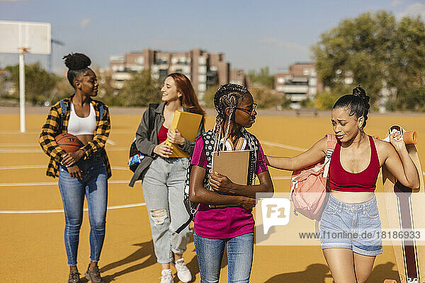 Sad woman walking with friends in sports court