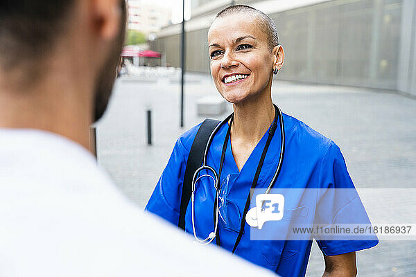 Smiling nurse with stethoscope talking to colleague