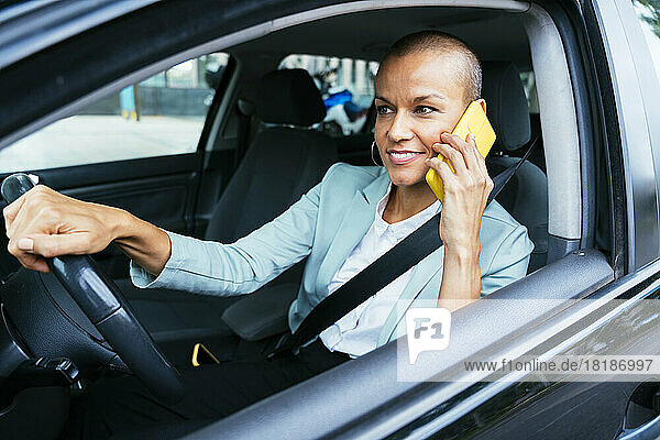 Smiling businesswoman talking on smart phone in car