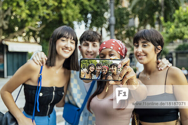 Woman showing her selfie on mobile phone with friends in park
