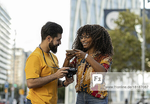 Smiling man with girlfriend photographing through smart phone