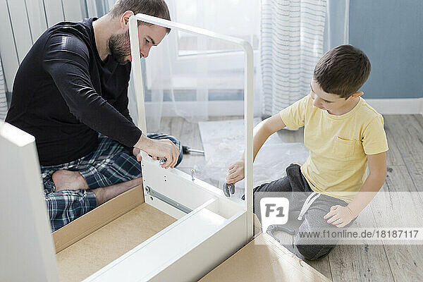 Father and son making table together at home