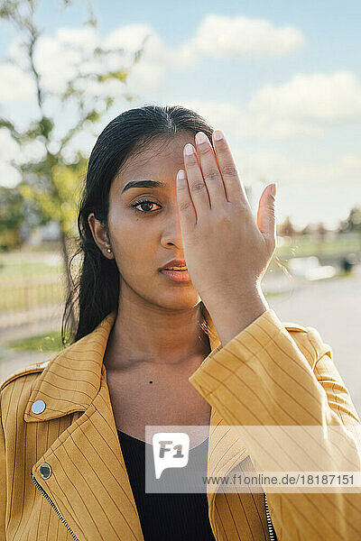 Woman covering face with hand on sunny day
