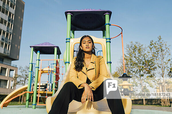 Young woman sitting on slide at playground