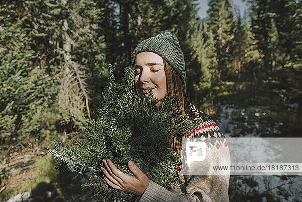 Woman with eyes closed holding twigs of spruce tree
