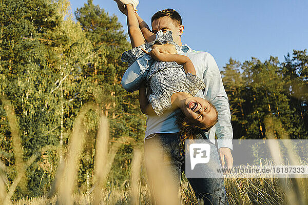 Happy father having fun with daughter at field
