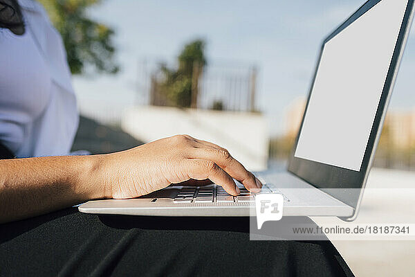 Hand of woman using laptop on sunny day