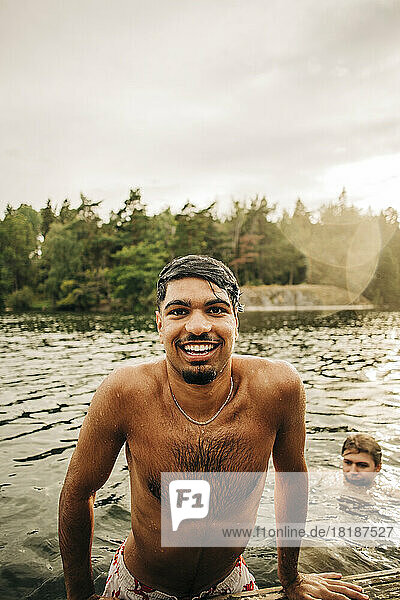Porträt eines nassen Mannes ohne Hemd  der im Urlaub mit einem männlichen Freund schwimmt