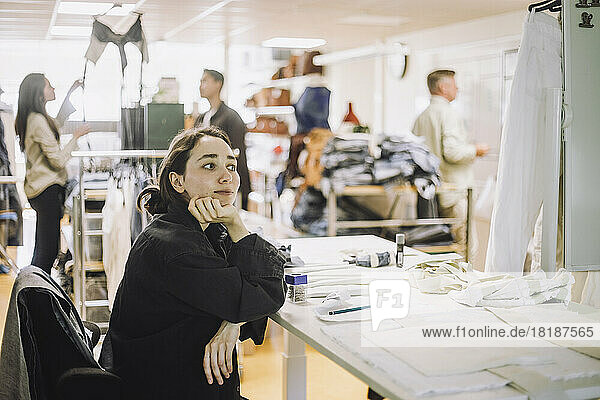 Thoughtful female fashion designer with hand on chin at workshop
