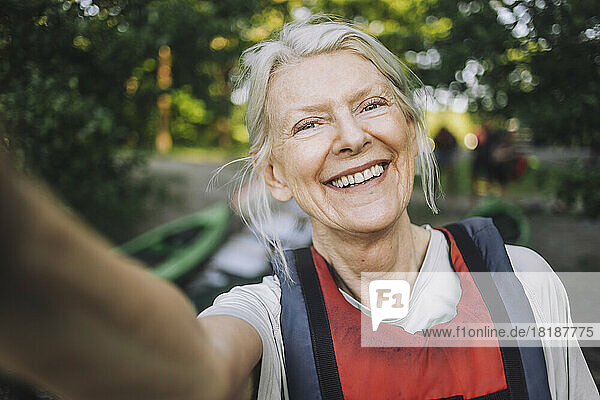 Glückliche ältere Frau  die ein Selfie mit Schwimmweste macht