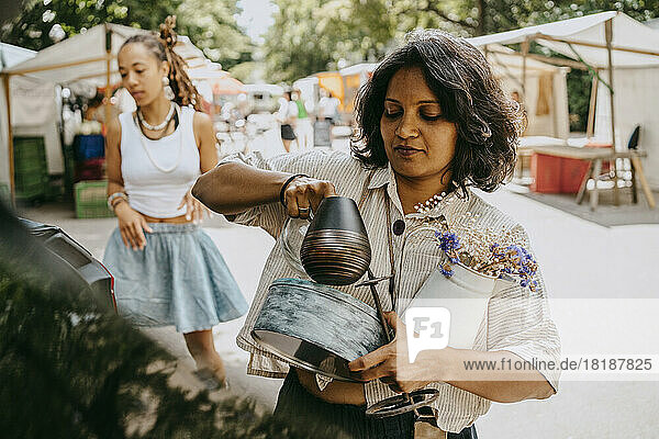 Frau trägt verschiedene Gegenstände beim Einkaufen auf dem Flohmarkt