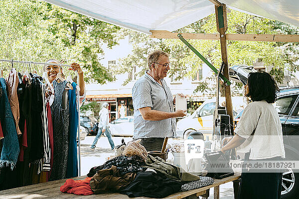 Älterer männlicher Kunde im Gespräch mit dem Besitzer in der Nähe eines Flohmarktstandes