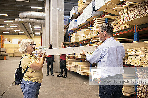 Senior man and woman choosing plank on rack at hardware store