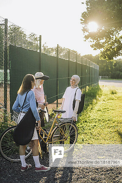 Ältere Frauen mit Fahrrad im Gespräch mit einer Freundin an einem sonnigen Tag
