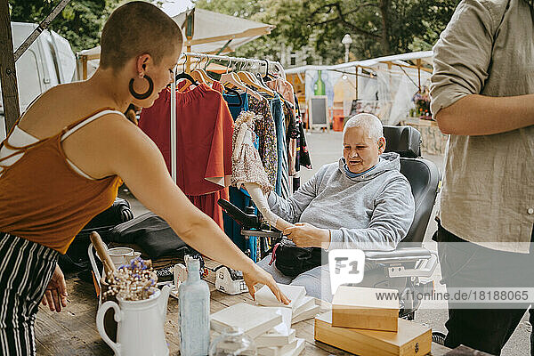 Weibliche Kundin mit Behinderung im Gespräch mit dem Besitzer beim Einkaufen auf dem Flohmarkt