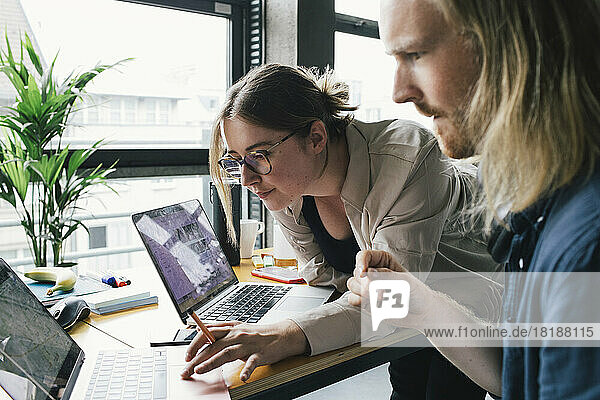 Businesswoman working on laptop with male colleague in startup company