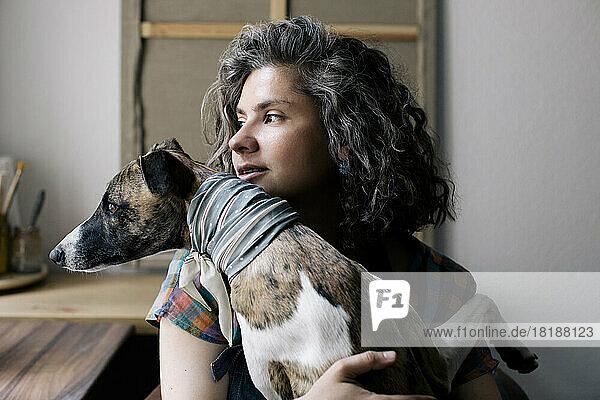 Woman looking away while sitting with dog at home
