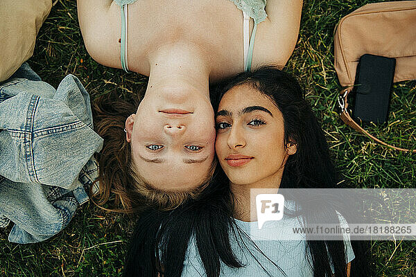 Porträt von Mädchen im Teenageralter  die zusammen auf dem Rasen eines Parks liegen