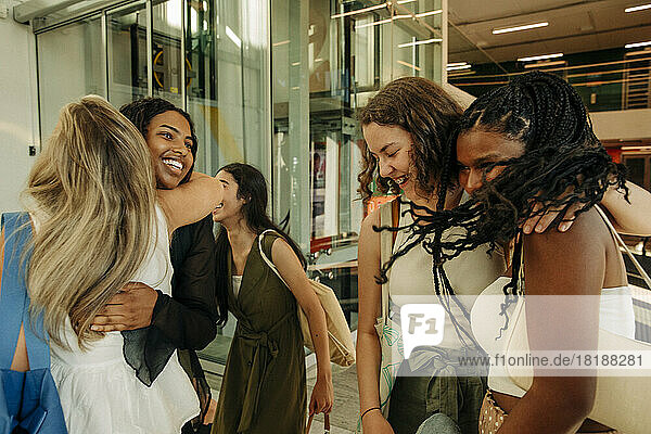 Glückliche Teenager-Mädchen grüßen sich gegenseitig  während sie sich in einem Einkaufszentrum vergnügen