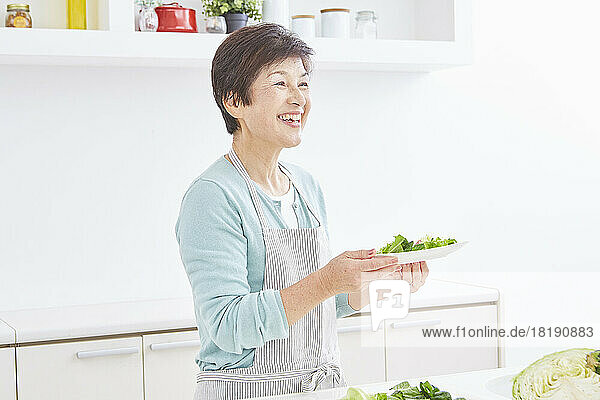 Japanese senior woman carrying serving of salad