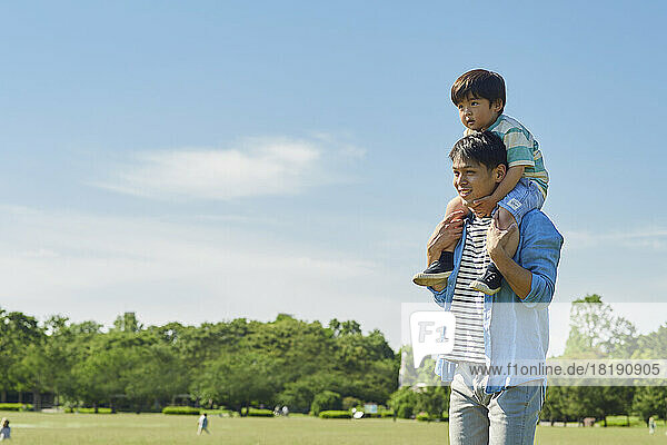 Japanese father carrying his son on his shoulders