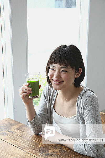 Young Japanese woman drinking a green smoothie