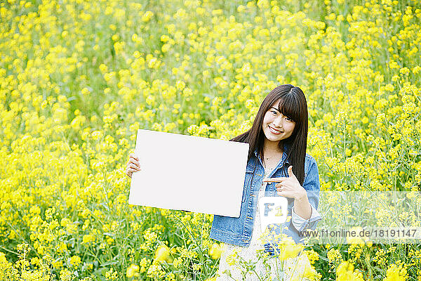 Japanese woman holding a white board in a field of flowers