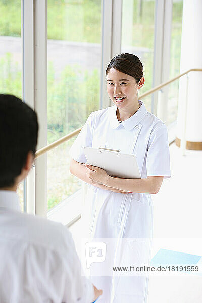 Smiling young female nurse having a conversation in the the hallway