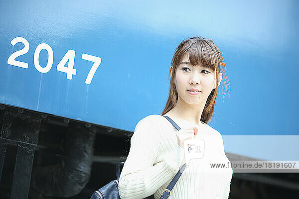 Japanese woman standing next to a train