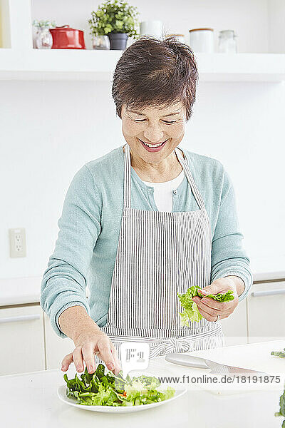 Japanese senior woman serving salad