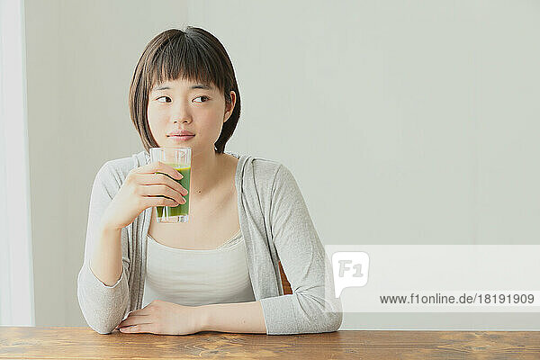 Young Japanese woman drinking green smoothie