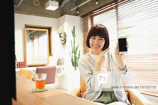 Young Japanese woman using mobile phone at beauty salon