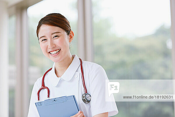 Smiling young Japanese female nurse walking in the corridor