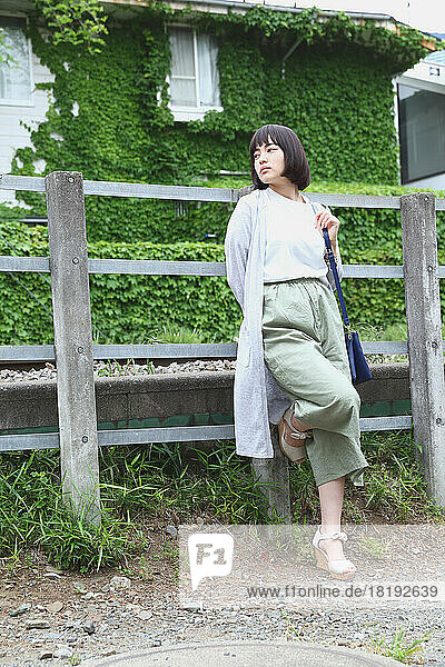 Young Japanese woman by the railway fence