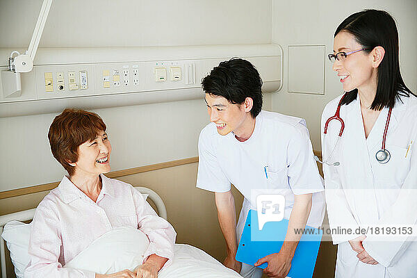 Senior woman being examined by a doctor and a nurse in a hospital room