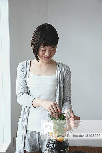 Young Japanese woman making a green smoothie