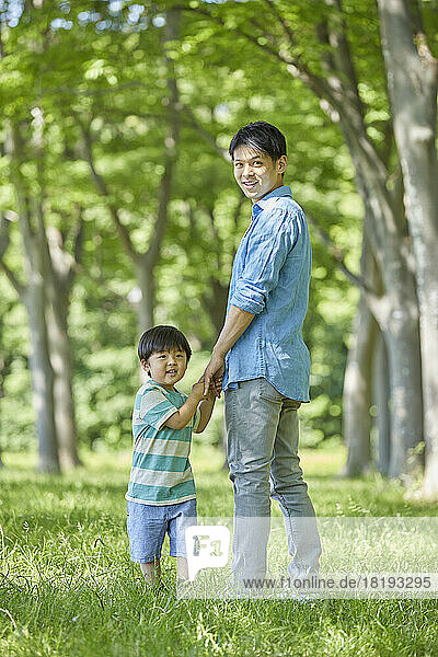 Japanese parent and child holding hands in fresh greenery