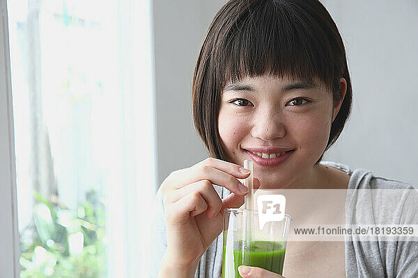 Young Japanese woman drinking a green smoothie