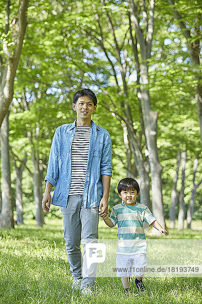 Japanese parent and child holding hands in fresh greenery