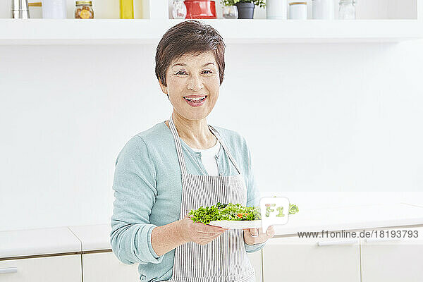 Japanese senior woman carrying serving of salad