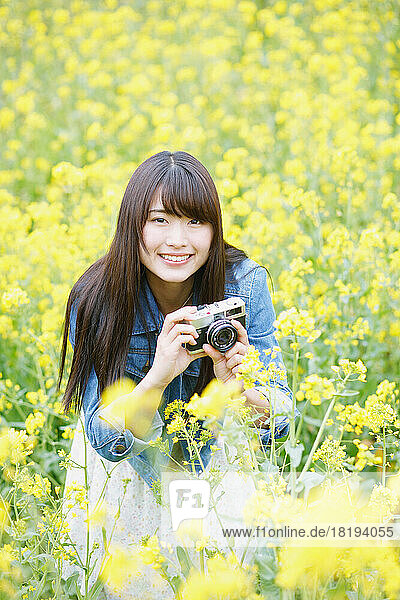 Young Japanese woman taking pictures in a field of blossoms
